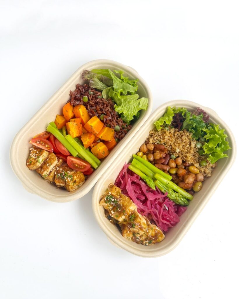 Two rectangular molded fiber containers filled with colorful foods.